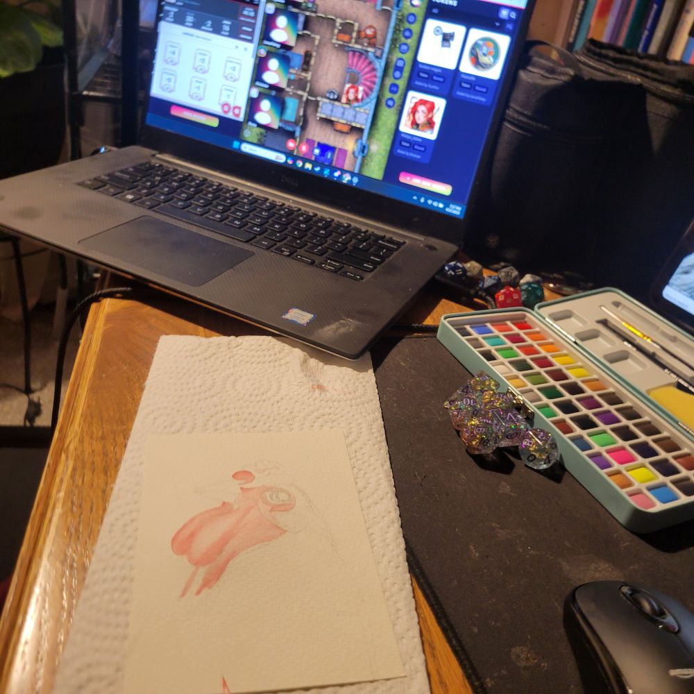 A photo of a desk with an in progress watercolor portait of a chicken in the foreground. Also on the desk is a laptop showing a dungeons and dragons map, a set of dice, and a watercolor set.