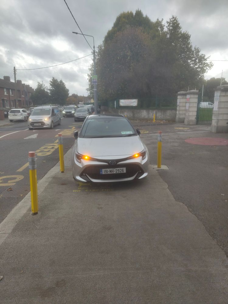 Car parked in between bollards outside a school