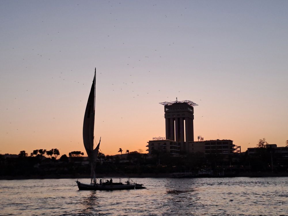 The Nile, with a sailboat shadowed against the sunset. Also shadowed, some building that I don't know and some trees.