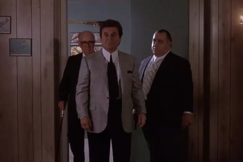 Scene from Goodfellas where Joe Pesci, in a suit, is being shown into an office by two guys in suits behind him