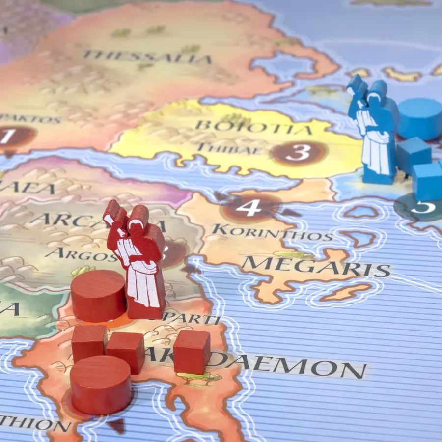 A close-up view of the board game Polis. Miniature wooden diplomats stand near their respective capitals.