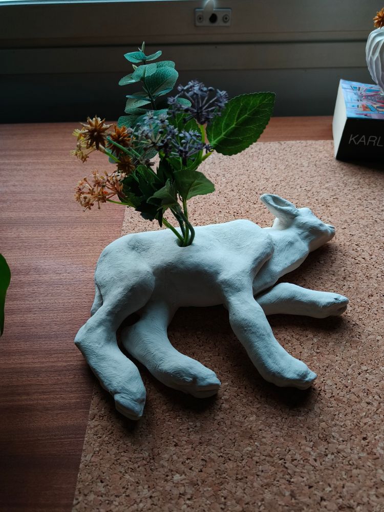 lammas vaasi. Valkoisesta savesta veistetty kyljellään makaava lammas-keramiikkatyö. Lammas on ontto sisältä, ja sen kyljessä on pieni reikä josta kukat näyttävät kasvavan.