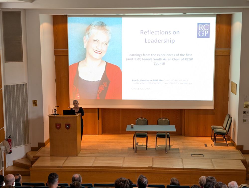 Professor Kamila Hawthorne gives a talk titled 'Reflections on Leadership' in a lecture hall, with a large projected slide featuring her photo and presentation title. Audience members are visible in the foreground.