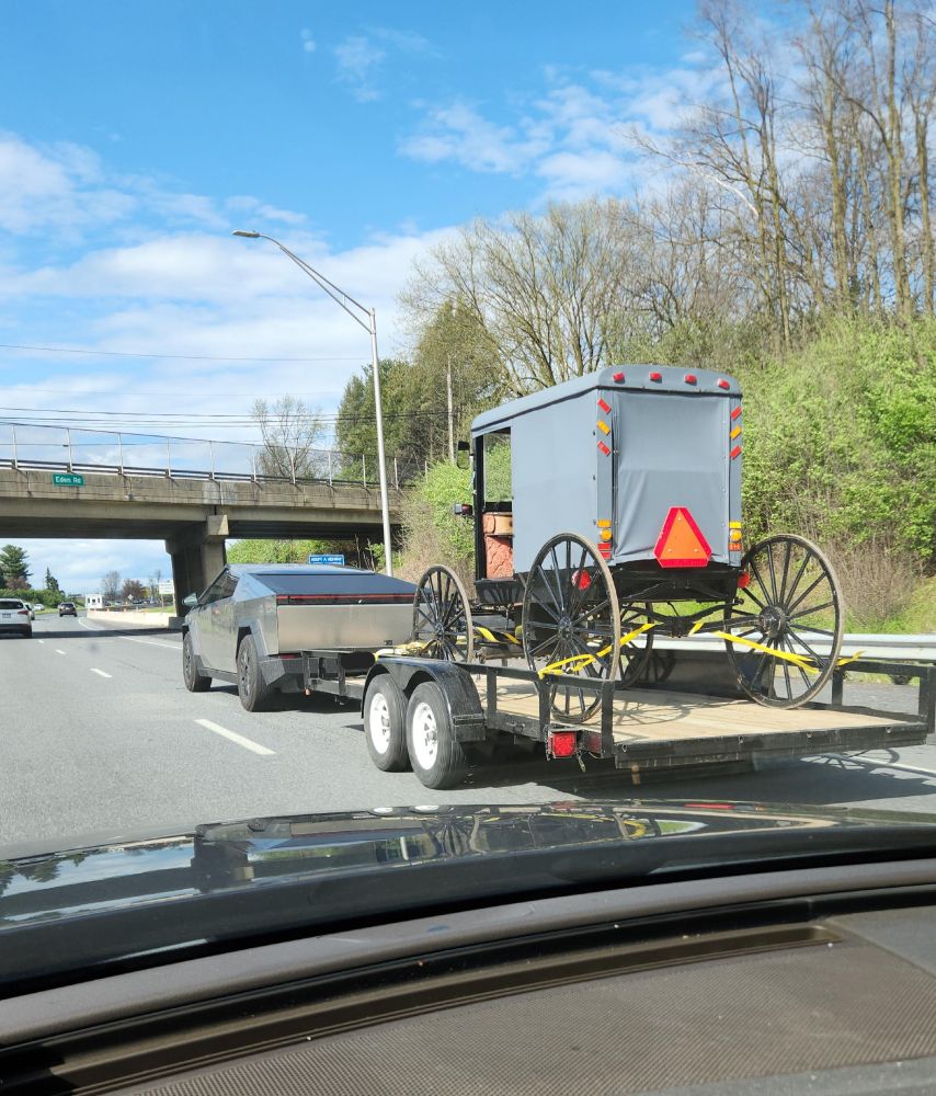 Tesla Cybertruck towing a horse carriage on the freeway.
