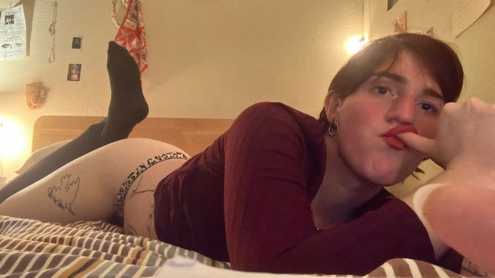 Same outfit and position as previous photo,, but Kit is cocked up a little on her elbow, thumb in her mouth accentuating full top lip with attitude. 