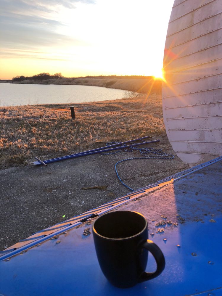 Black tea mug on the blue airplane stabilizer with the sun setting 