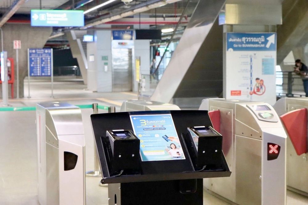 Two EMV payment terminals on podium in front of fare gates