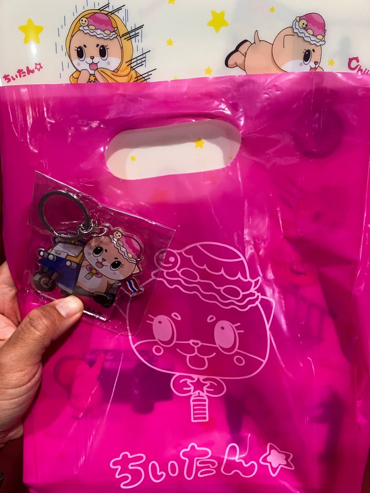 Key ring of chittan in a tuk tuk and a file folder showing chiitan’s antics