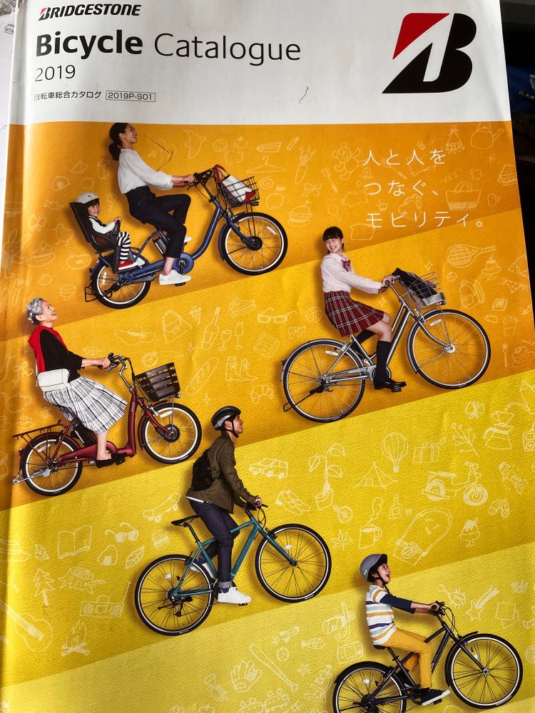 Bridgestone bicycle catalogue featuring people riding various bikes: a mother with child in rear seat, an elderly woman, a school girl, a man, a boy