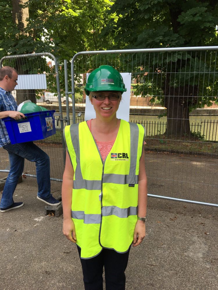 Me, wearing high viz and a hard hat, in front of a building site in Reading as part of my first site visit working for the National Lottery Heritage Fund