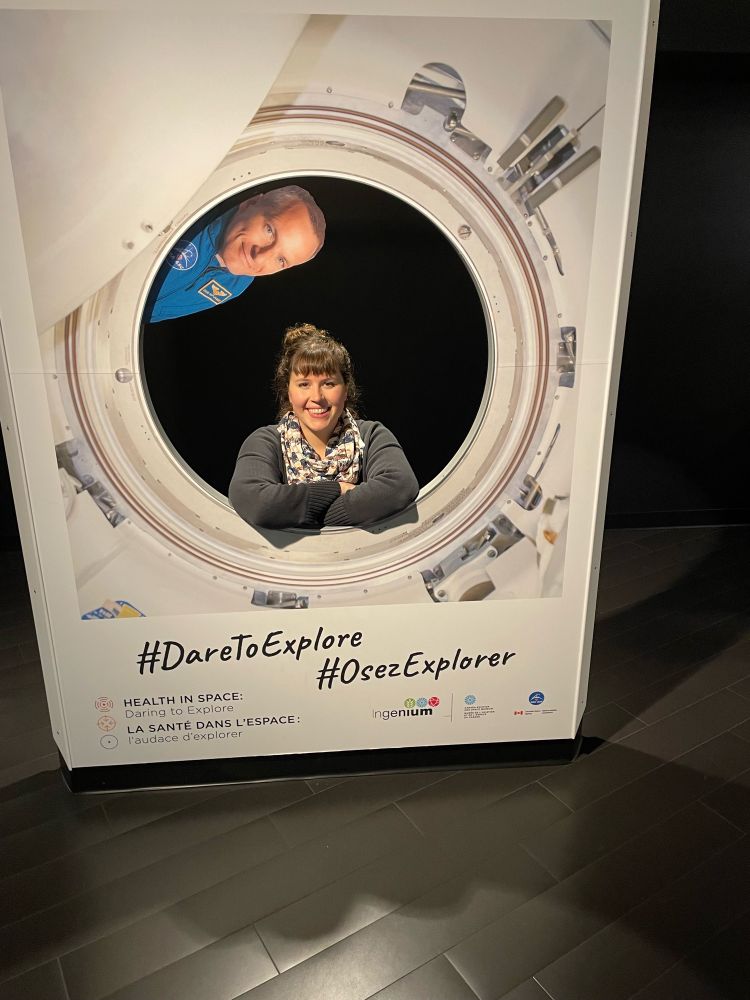 Smiling woman with scarf kneels in center of pretend window with astronaut from space shuttle 