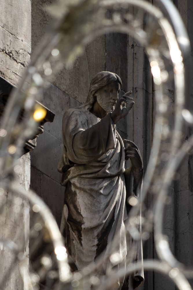 Estatua de Sagrado Corazón de Cristo enmarcado en unas luces de fiesta popular apagadas.