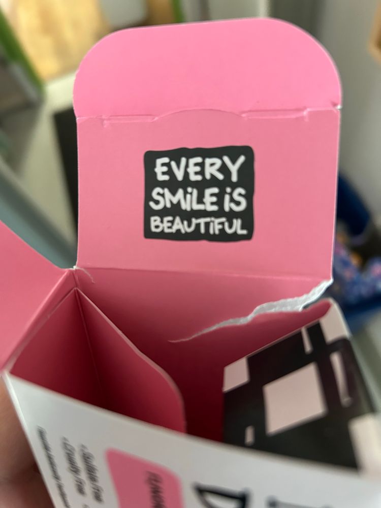 There is a cardboard kids toothpaste box, and on the inside of a flap it says: EVERY
SMiLE iS BEAUTiFUL