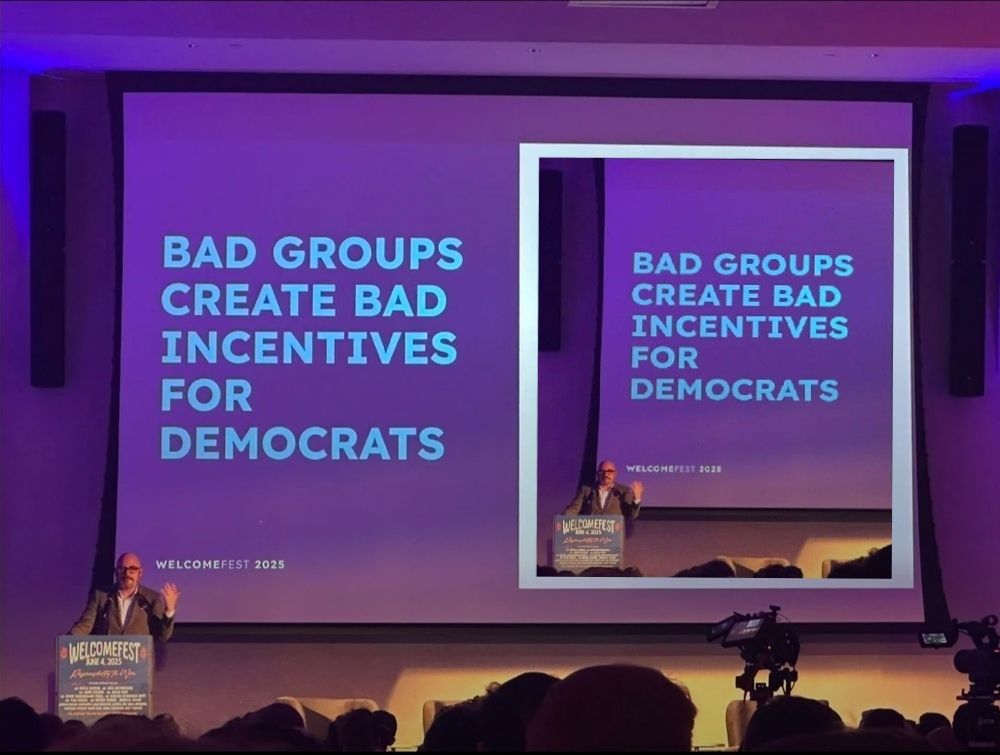 Matt Yglesias giving a speech at WelcomeFest 2025 in front of a PowerPoint slide saying "Bad Groups Create Bad Incentives for Democrats," but with his example on the slide being replaced with himself standing in front of the same slide.