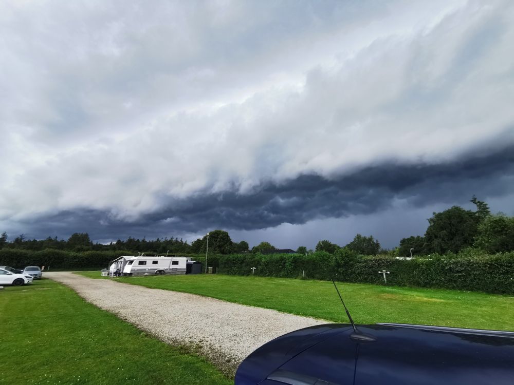 lange dunkle Wolkenfront über einem Campingplatz mit Wohnwagen