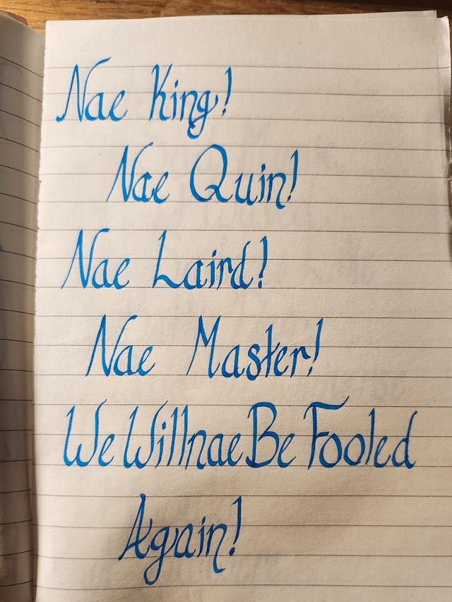 A picture of handwrieen text on a page in beautiful blue calligraphy. It reads: "Nae king! Nae quin! Nae laird! Nae master! We willnae be fooled again!”