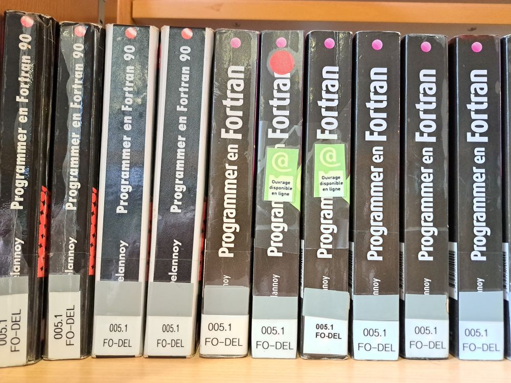 Une série de (vieux) livres de programmation vus par la tranche, montrant les titres "programmer en Fortran 90" et "Programmer en Fortran"