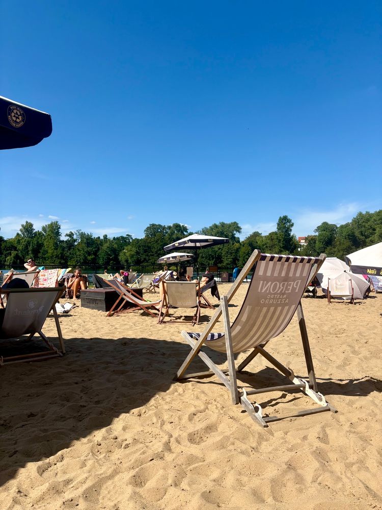 Blue skies, sand, deckchairs and a lake a in the distance. 