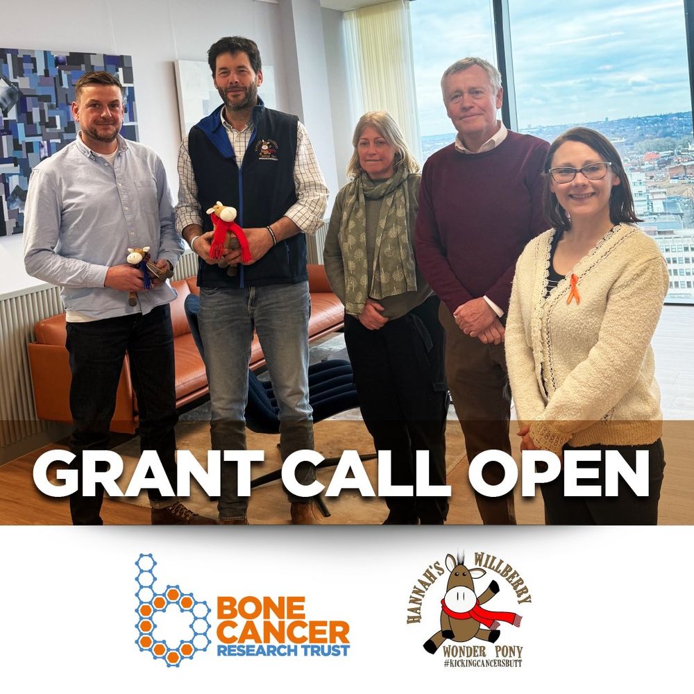 Five members of Hannah's Willberry Wonder Pony and the Bone Cancer Research Trust pose for a photograph whilst smiling at the camera. Two of them are holding Berry Pony mascots and one of them is wearing a Bone Cancer Research Trust awareness ribbon.