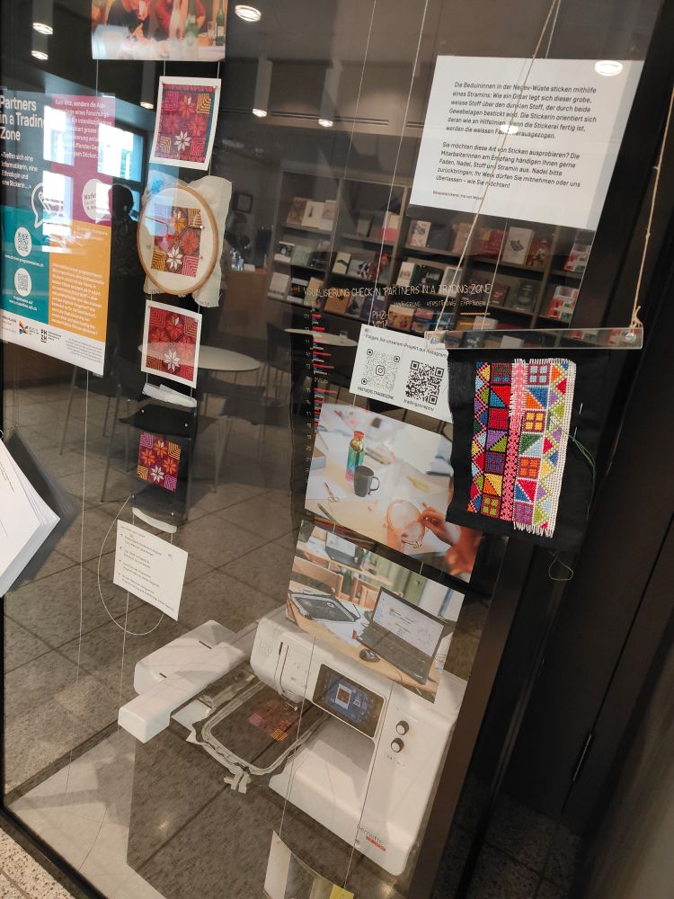 Display glass cabinet with pieces of textile embroidery art and printed information inside. 