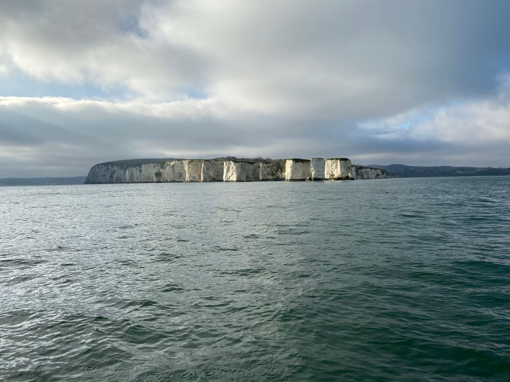 Side view of Old Harry Rocks in Studland, Dorset, taken from the water in January. The white chalk cliffs and their sharp edges stand out against moody, overcast clouds above the Jurassic Coast.