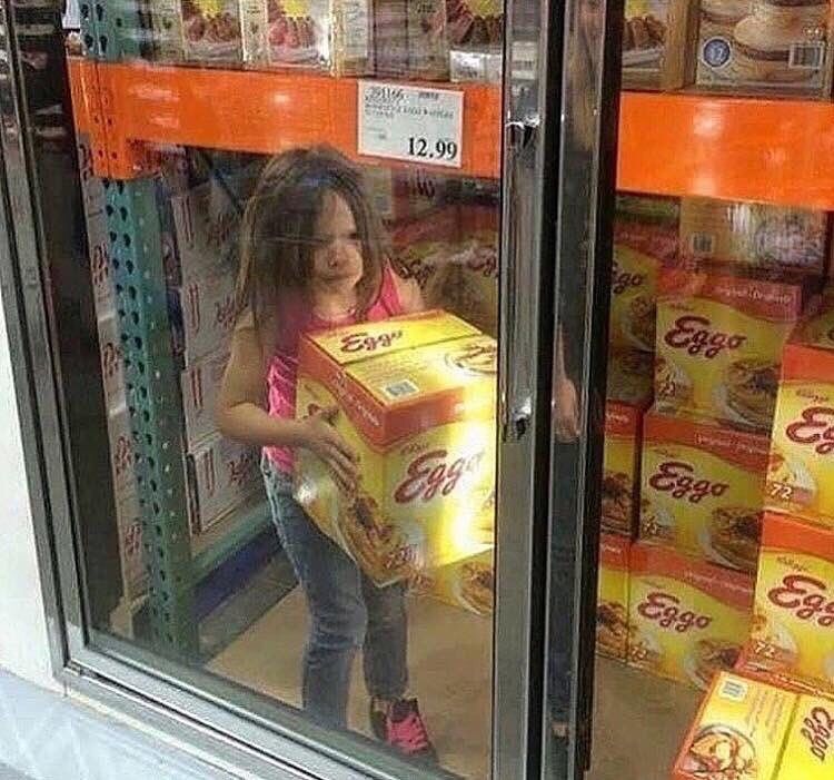 A child holding a huge box of Eggos in a walk-in freezer.