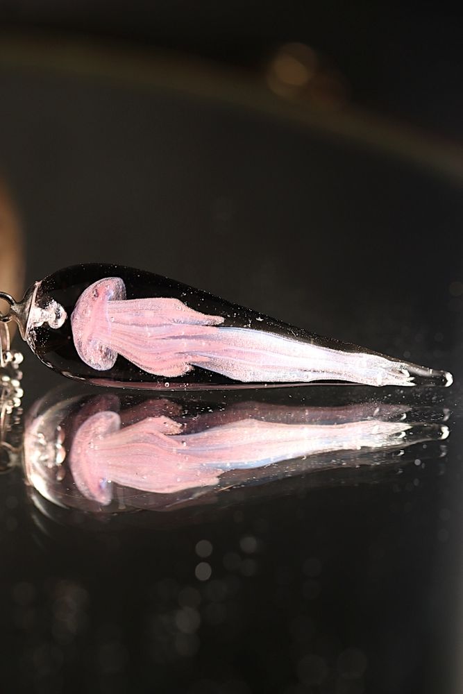 Pendentif en forme de goutte avec une méduse de couleur rose en apesanteur dans la goutte. 