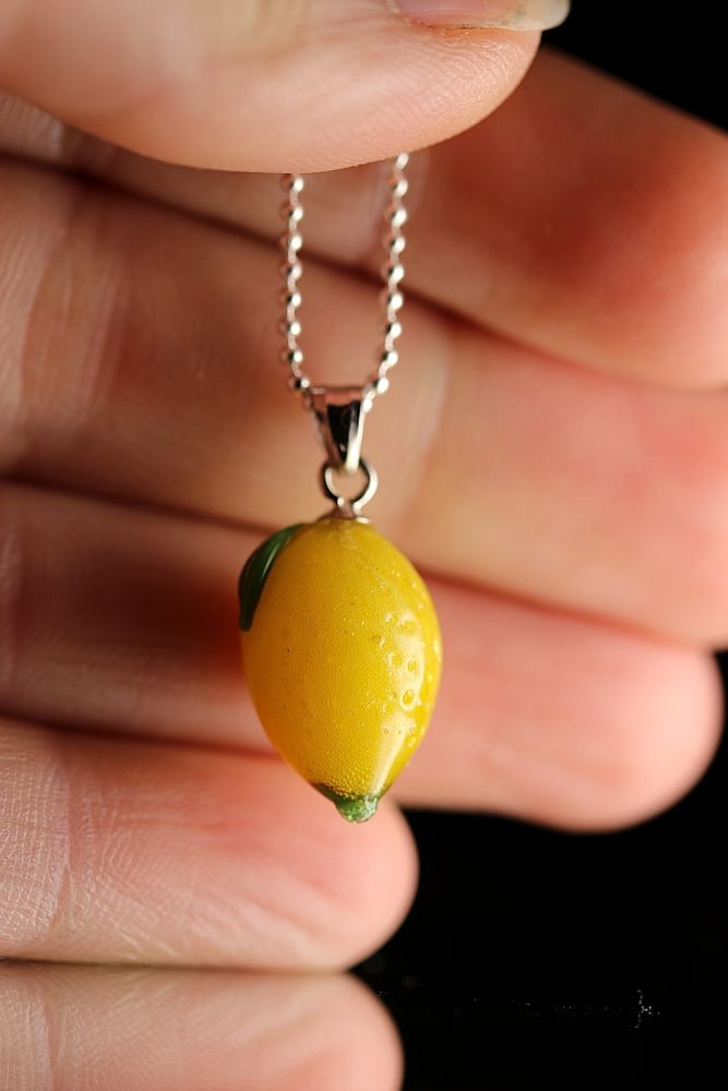 Pendentif qui représente un mini citron posé sur la main de la créatrice qui permet d’évaluer la taille du citron. 

Le mini citron est associé à une chaîne en argent 925 pour un effet des plus élégant .

Le citron à une petite feuille de couleur vert posé sur le citron.
