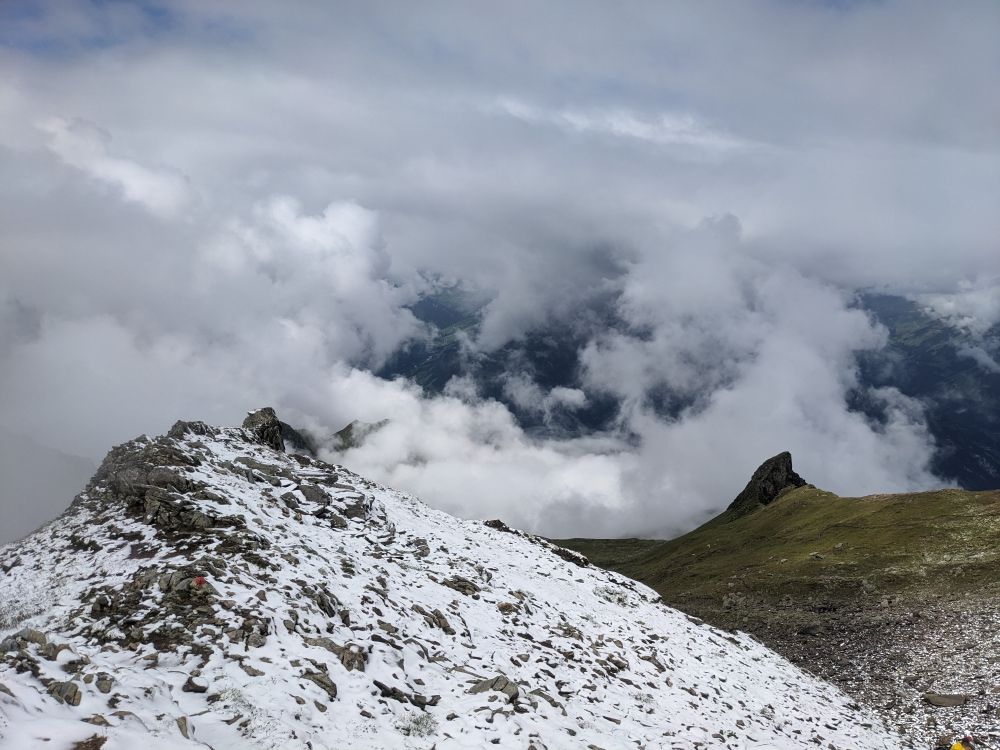 looking down from mountain, with snow, clouds, and a spire