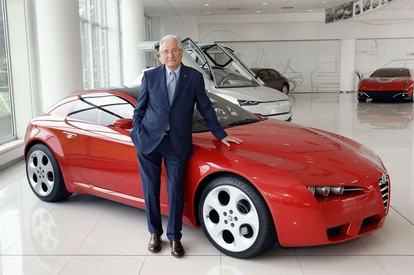Giorgetto Giugiaro standing and leaning onto one of his designs: a red Alfa Romeo Brera concept.