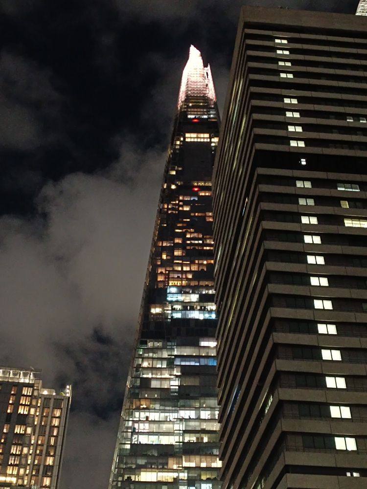 Night time view of the Shard looking up. The top point is lit up bright white, many windows are lit up too. The overall effect is more eye of Sauron than cheerful Christmas lighting. 
