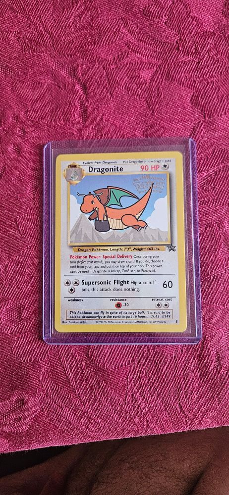 A pokemon card featuring Dragonite. An orange dragon with a mail bag flying over some mountains. There is text in the bottom half of the card.