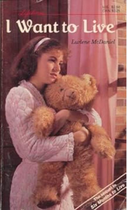 The cover of Lurlene McDaniel's novel I Want to Live, depicting a girl in a pink bathrobe holding a teddy bear and looking out a window.