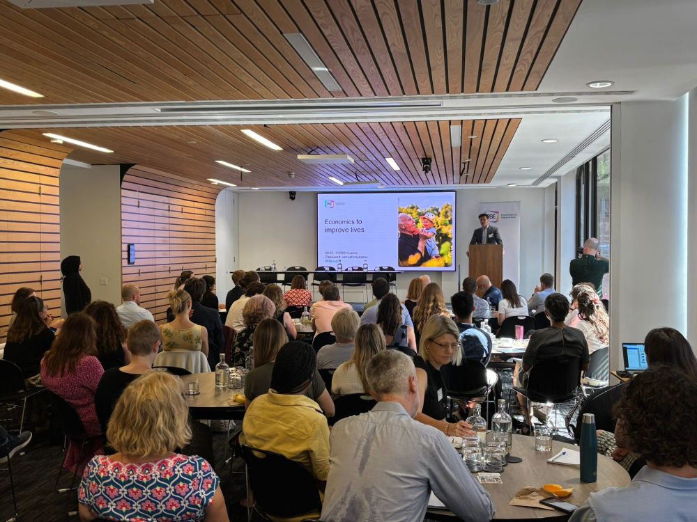 A room full of people looking toward a stage, where a presentation is underway