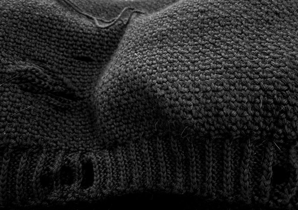 Bottom edge of my crochet black distressed sweater with a distressed ribbed edge.