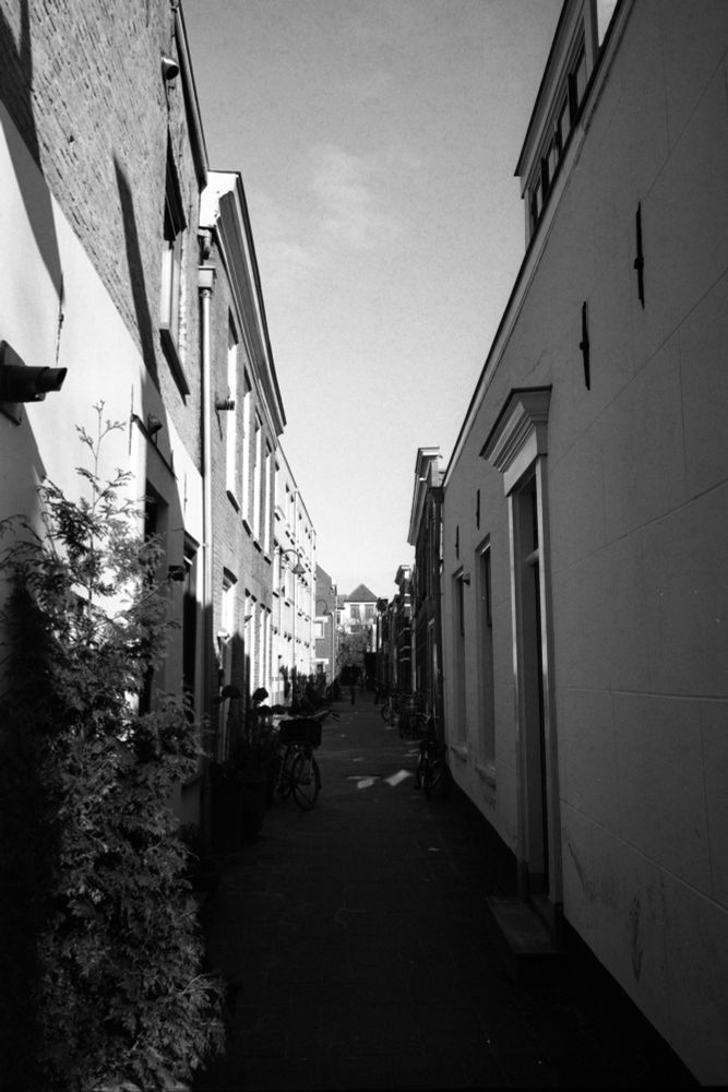 A black and white photo of a street with old houses, barely wider than a single horse and cart