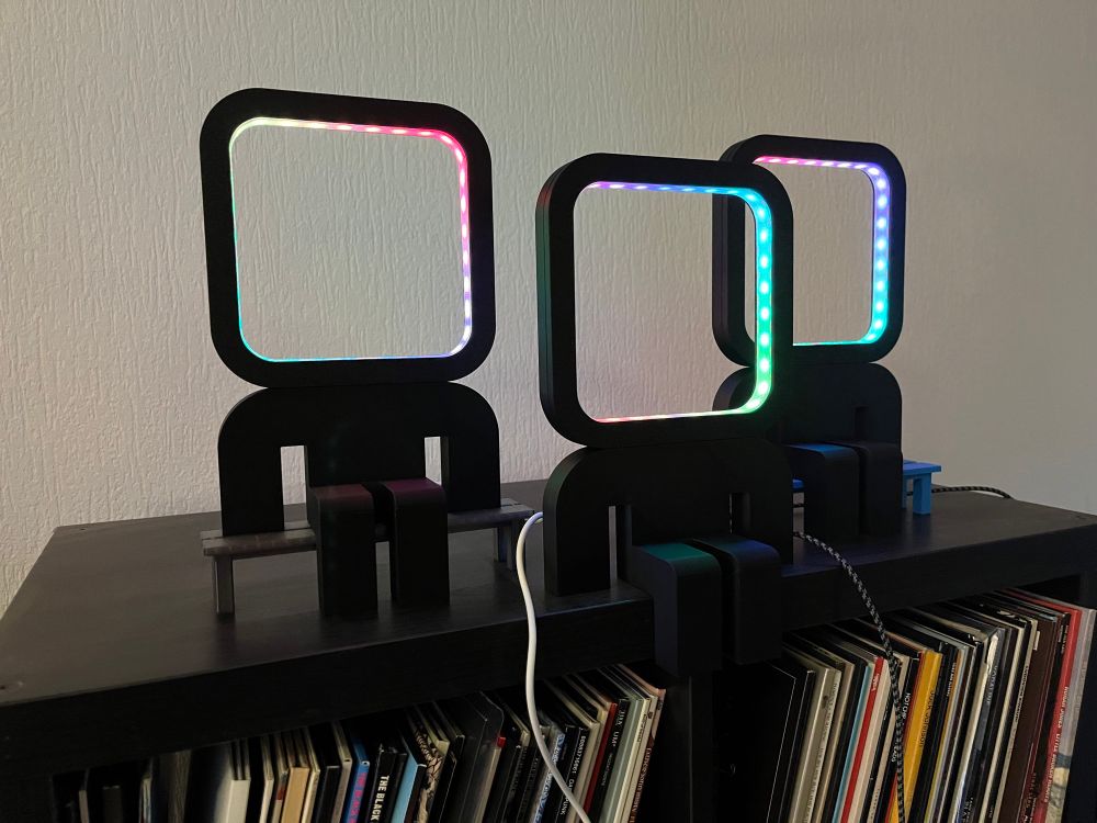 Three abstract figures with an rgb light as a head sitting on a record cabinet