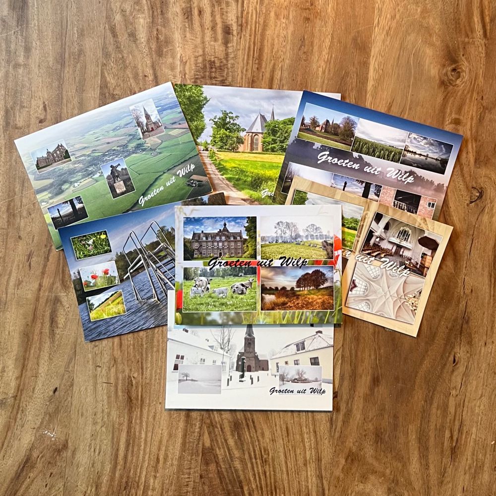 Een verzameling ansichtkaarten met foto’s van landschappen en gebouwen, met de tekst “Groeten uit Wilp”, uitgestald op een houten ondergrond.