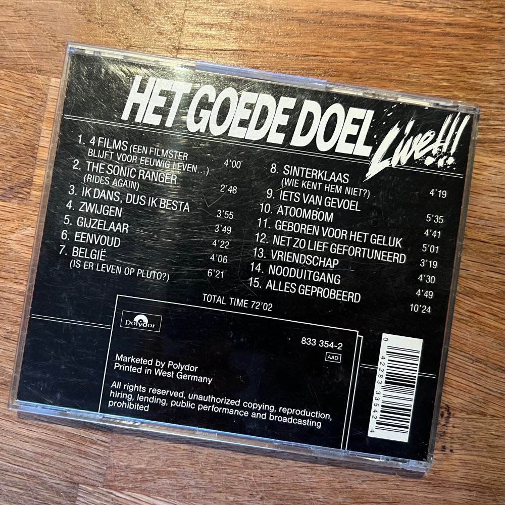 Achterkant van de CD “Het Goede Doel Live!!!” met een lijst van 15 live-uitvoeringen, inclusief titels en speelduur. Te zien zijn onder andere “4 FILMS”, “BELGIË”, “SINTERKLAAS” en “ALLES GEPROBEERD”. Onderaan staan technische gegevens zoals het Polydor-label, barcode en copyrightinformatie.

“Eenvoud is onuitputtelijk.“ ~ Krishnamurti
