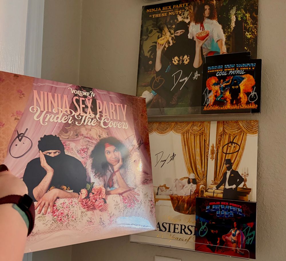 A photo depicting several Ninja Sex Party records and CDs, signed by Danny Sexbang (Dan Avidan) and Ninja Brian (Dr. Brian Wecht). The albums include Cool Patrol, Level Up, These Nuts, Masterstrokes, and now Under the Covers Vol 4.