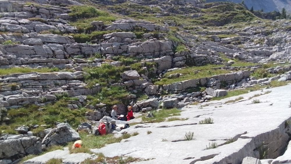 Karst plane with two cavers looking out of a cave.