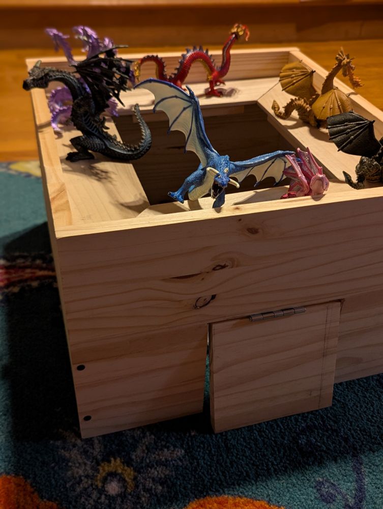 A square castle with a door that swings open and a balcony around the inside for the dragons to look out from. There are plastic dragons on it. 