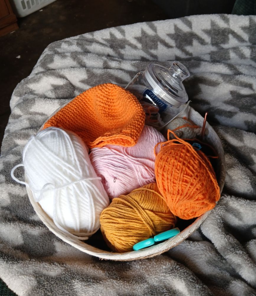 A basket full of yarn sits on a soft blanket