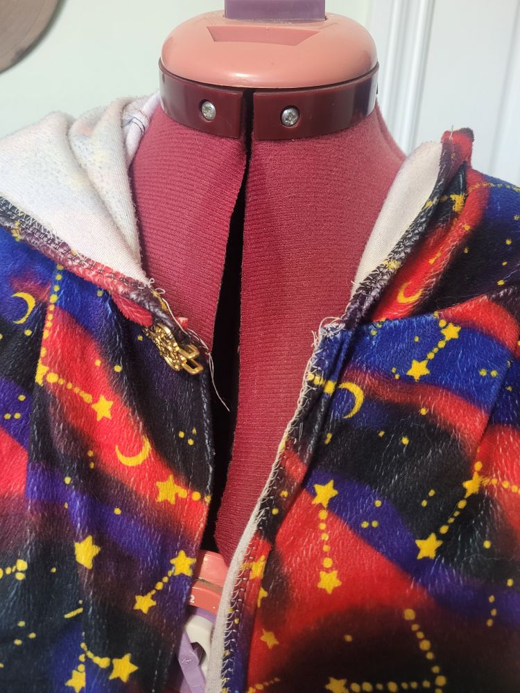 A close-up before photo of a cloak I was commissioned to add a lining to. The stitching is messy, the clasp is broken, and the cloak was made from a single sheet of flannelette.