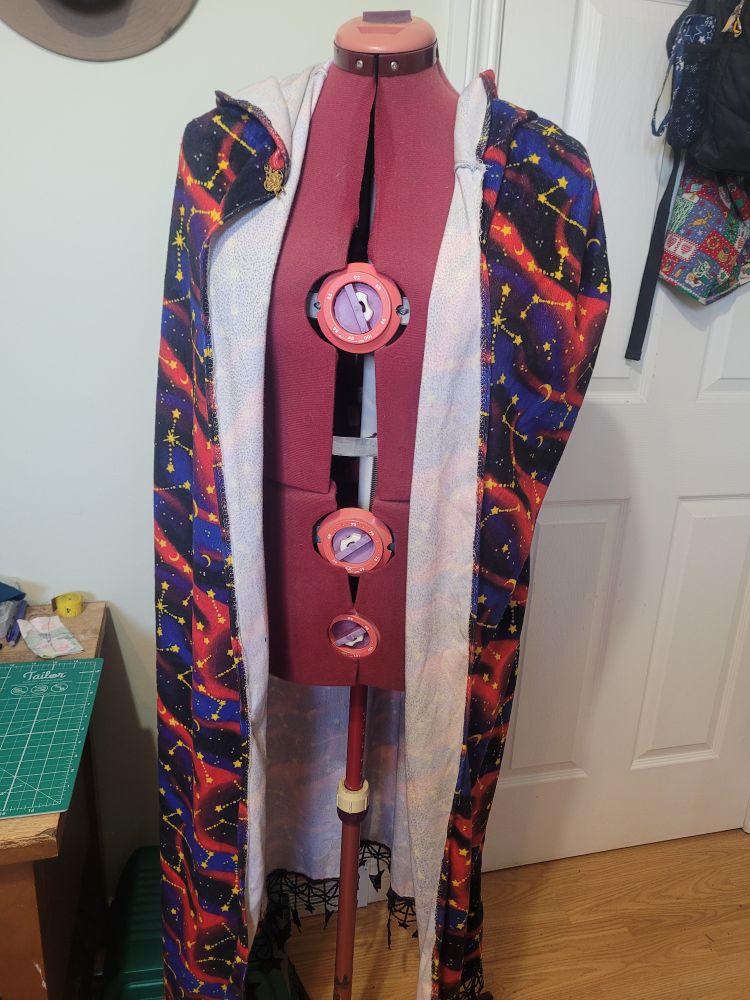 A full view of the cloak before being worked on. The galactic constellation pattern on the outside of the cloak is visible from the inside, and the cloak sits crooked around the shoulders.
