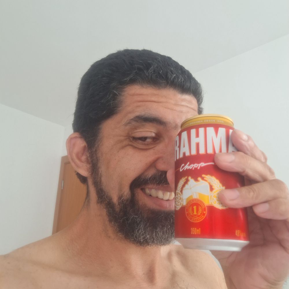 Selfie. Estou sorrindo segurando uma lata de Brahma que cobre parte do rosto. Estou sem camiseta, mas a foto só mostra parte dos ombros