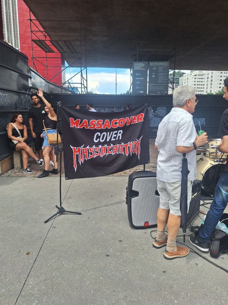 Foto tirada em frente aoxvão livre do Masp. Em destaque uma faixa preta onde se lê: 

Massacover
Cover 
Massacration
