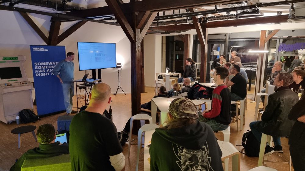 Group of developers sitting and standing around, watching a presentation 