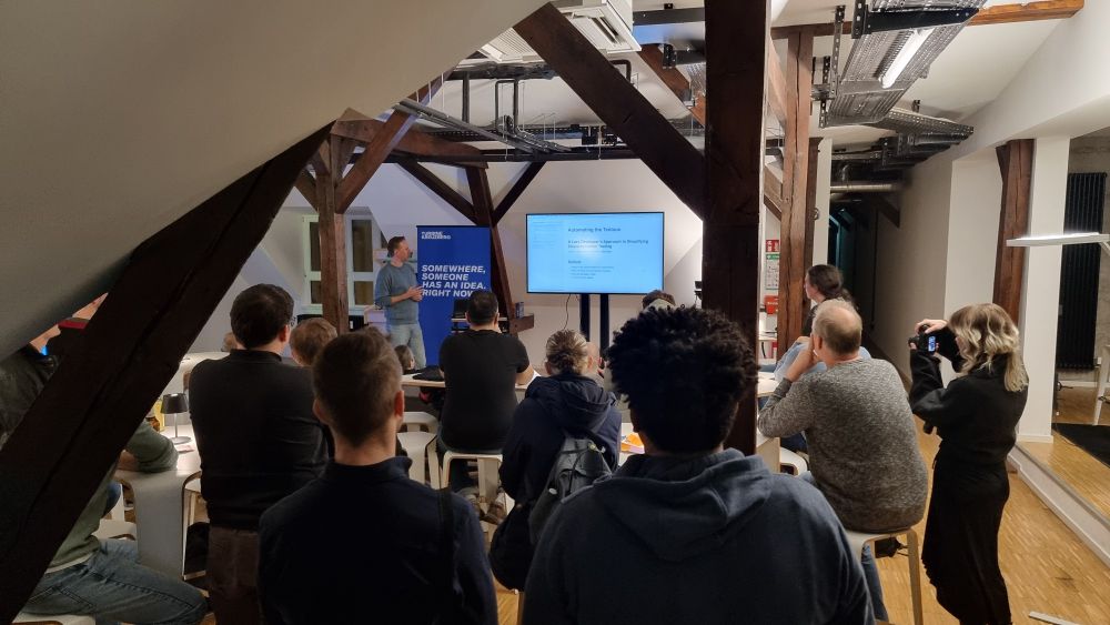 Group of developers sitting and standing around, watching a presentation 