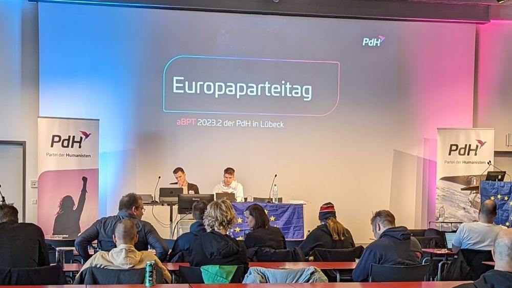 Foto vom Europaparteitag der PdH. Blick auf das Podium, Teil des Publikums ist auch im Bild